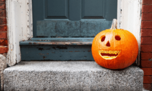 Carved jack-o-lantern pumpkin with a cheerful smile displayed on a doorstep for Halloween.