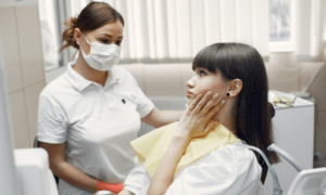 Dental professional examining patient's jaw and mouth for signs of emergency dental care.