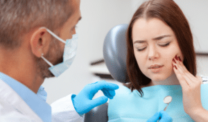 Dentist examining female patient's teeth in clinical office setting with blue headrest