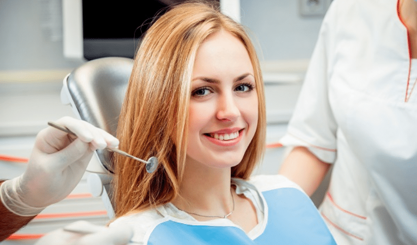 Dentist examining patient's teeth during routine dental checkup in clinical setting.