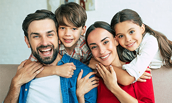 Happy family of four smiling together indoors at dental center